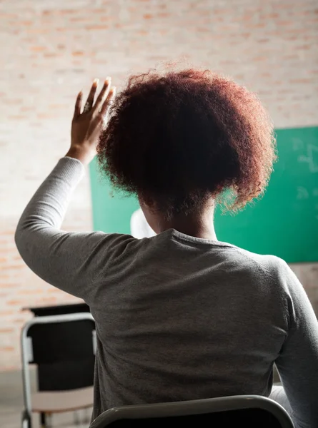 Kvinnlig student höja handen till svar i klassrummet — Stockfoto