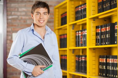 Kendine güvenen öğrenci kitap dururken kampüs içinde tutan