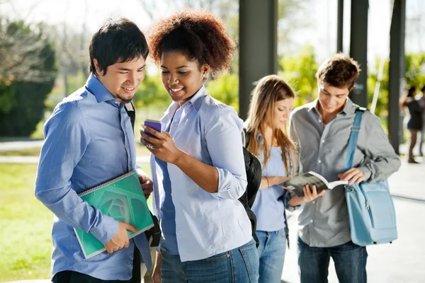 Students Reading Text Message On Mobilephone In Campus