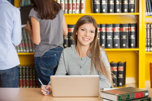 Donna con computer portatile seduto a tavola nella biblioteca del college — Foto Stock