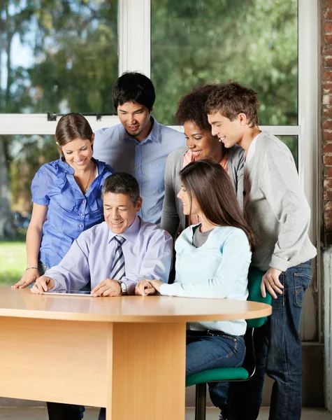 Studenti e insegnanti guardando la tavoletta digitale in classe — Foto Stock