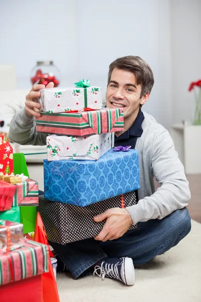 Homem com pilha de presentes de Natal em casa — Fotografia de Stock