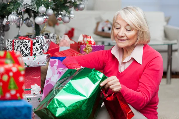 Женщина смотрит в мешок, сидя на Рождество подарки — стоковое фото