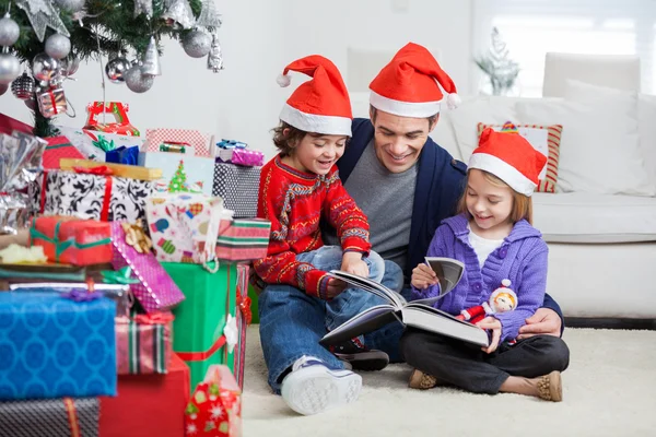 Broers en zussen en vader lezen boek door Kerst presenteert — Stockfoto