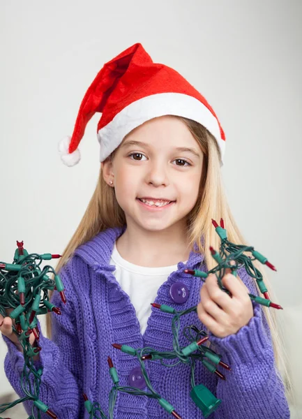 Chica en Santa Sombrero sosteniendo luces de hadas — Foto de Stock