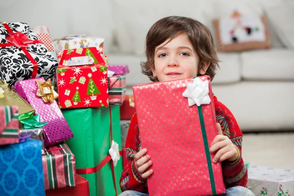 積み上げクリスマスまで座っている少年を提示します。 — ストック写真