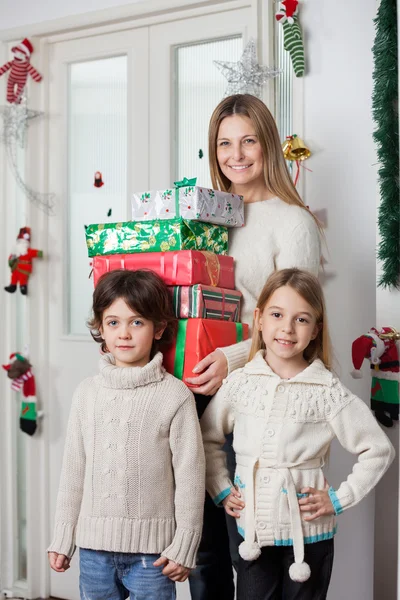 Familie met geschenken permanent door de deur tijdens Kerstmis — Stockfoto