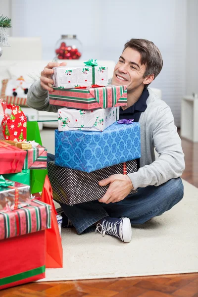 Lächelnder Mann mit Stapel Weihnachtsgeschenken — Stockfoto