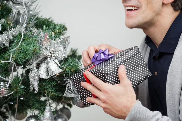 Man met heden door kerstboom thuis — Stockfoto