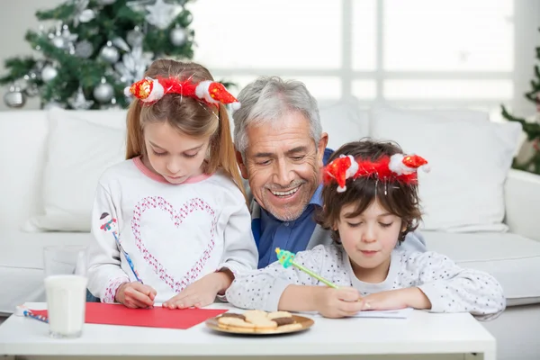 Дедушка помогал детям в написании писем Санта Клаусу — стоковое фото