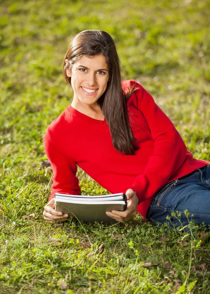 Frau mit Büchern entspannt sich auf Rasen auf College-Campus — Stockfoto