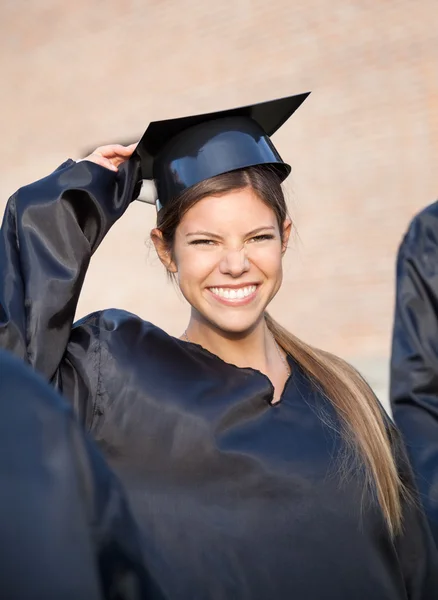 Mulher em vestido de graduação segurando placa de argamassa no campus — Fotografia de Stock