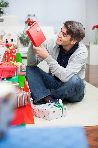 Мужчина смотрит на подарок на Рождество в доме — стоковое фото