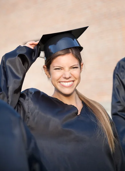 Woman In Graduation Gown Holding Mortar Board On Campus Stock Picture