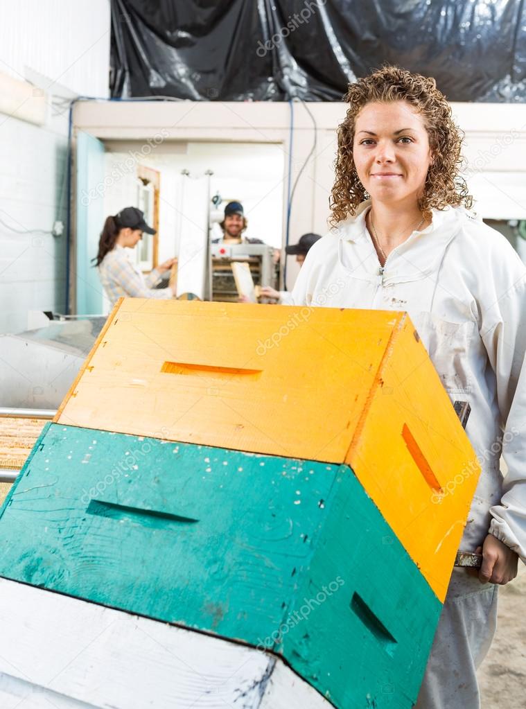 Female Beekeeper Holding Trolley Of Stacked Honeycomb Crates