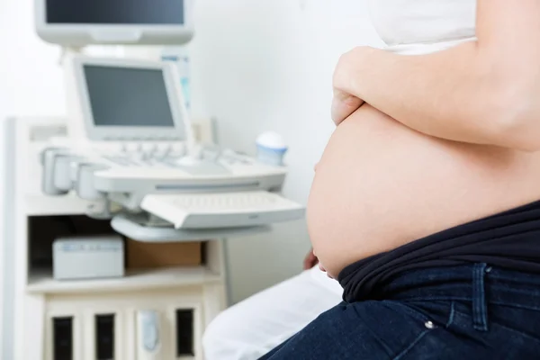 Gravid kvinna med ultraljudsmaskinen i bakgrunden — Stockfoto