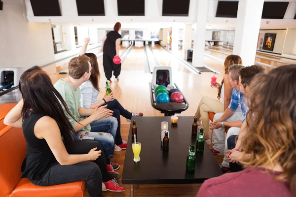 Amis regardant Woman Bowling en club — Photo