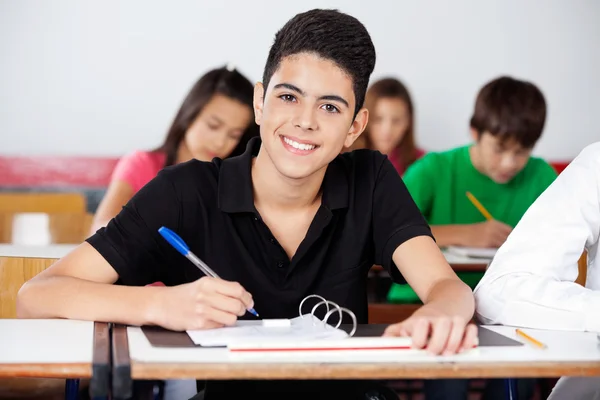 Adolescent écolier écriture dans classeur à bureau — Photo