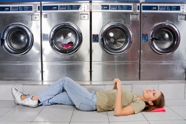 Frau hört Musik, während sie an der Wäsche liegt — Stockfoto