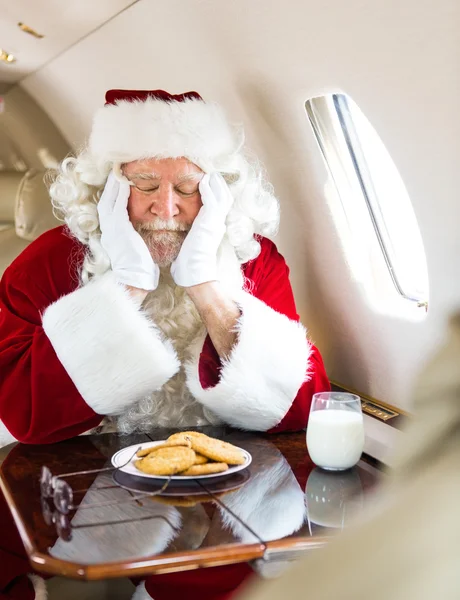 Santa con galletas y leche durmiendo en jet privado —  Fotos de Stock