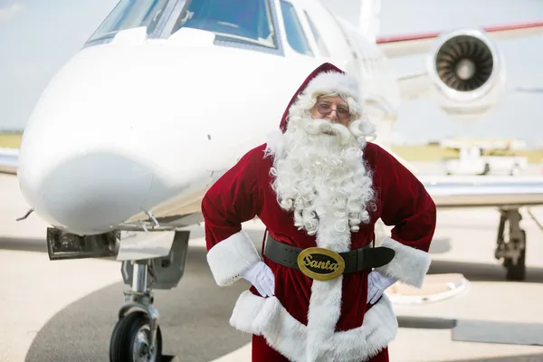 Santa con las manos en la cadera contra jet privado — Foto de Stock