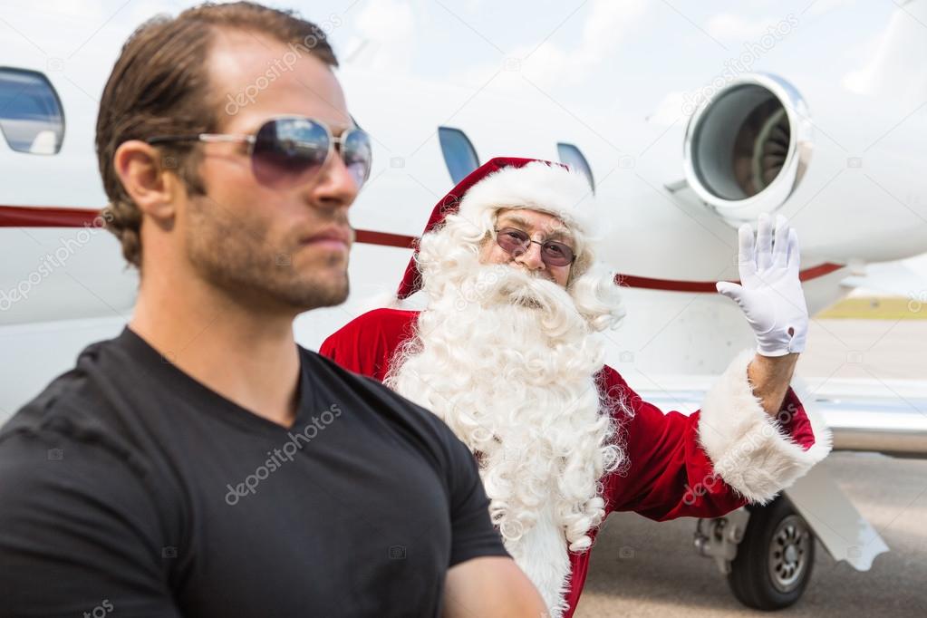 Santa Waving Hand With Bodyguard In Foreground Against Private J