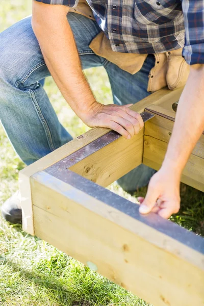 Trabalhador manual que mede a madeira com escala no local de construção — Fotografia de Stock