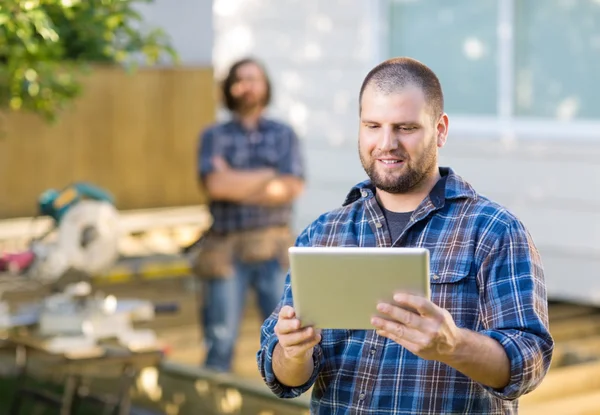 Backgro içinde duran iş arkadaşınız ile dijital tablet kullanarak bir marangoz — Stok fotoğraf