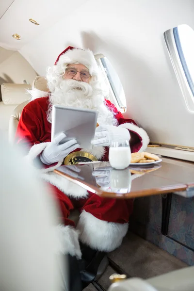 Santa Holding Digital Tablet In Private Jet — Stock Photo, Image