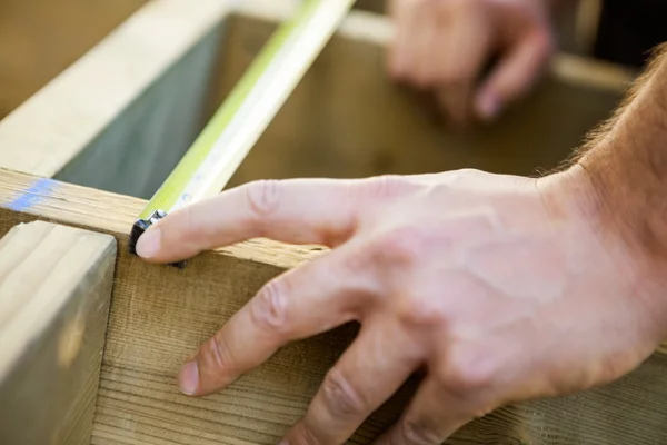 Mano del carpintero que mide madera con cinta —  Fotos de Stock