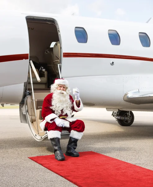 Santa Toasting verre de lait tout en étant assis sur l'échelle du jet privé — Photo