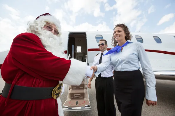 Airhostess i pilot powitanie santa przeciwko prywatny odrzutowiec — Zdjęcie stockowe