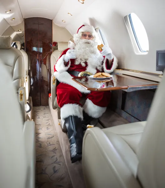 Weihnachtsmann mit Keksen und Milch im Privatjet — Stockfoto