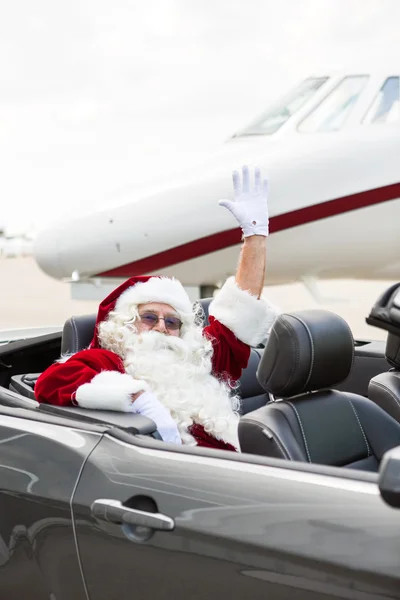 Santa agitant la main dans Convertible contre Jet privé — Photo