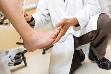 Doctor Examining Patient's Foot In Hospital