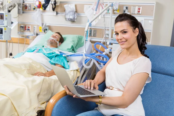 Kobieta z laptopa siedzi mężczyzna pacjenta w szpitalu — Zdjęcie stockowe