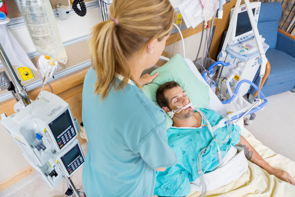 Nurse Adjusting Young Patient's Pillow In Hospital