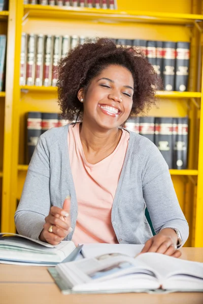 Studente con gli occhi chiusi seduto a tavola in biblioteca — Foto Stock