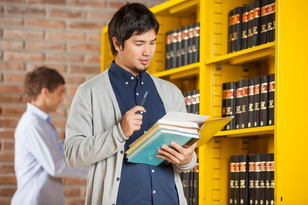 Manlig student läsa bok i college library — Stockfoto