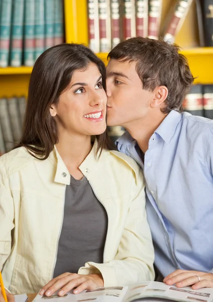 Homem beijar namorada no faculdade biblioteca — Fotografia de Stock