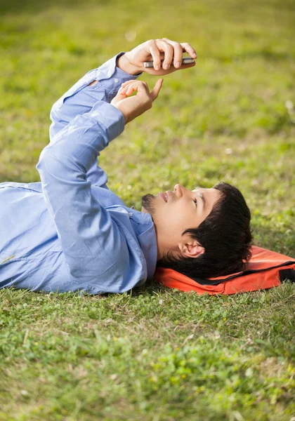 Student SMS på mobiltelefon liggande på campus — Stockfoto