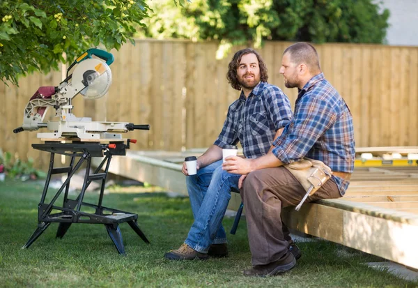 Lavoratori che tengono tazze di caffè usa e getta su telaio in legno — Foto Stock