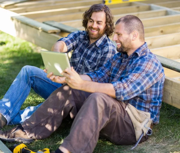 Carpinteros felices usando tableta digital en el sitio de construcción —  Fotos de Stock