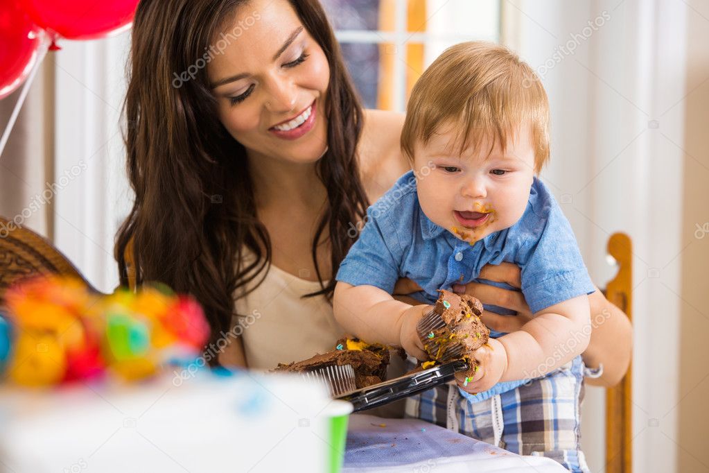 Mother Holding Baby Boy Eating Cupcake