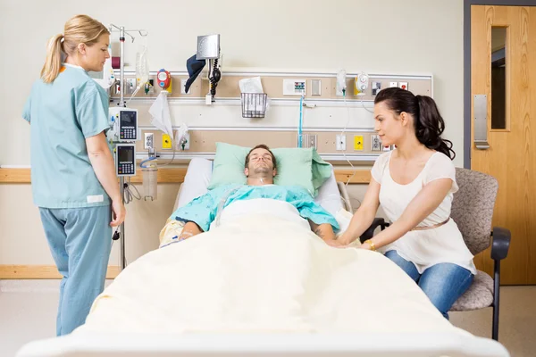 Mujer sosteniendo la mano del paciente en la habitación del hospital —  Fotos de Stock