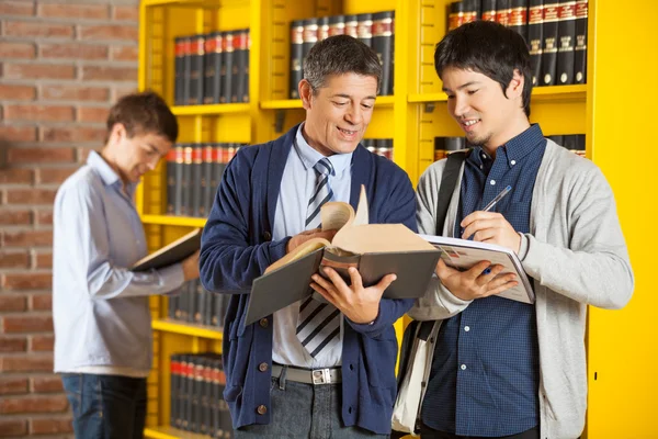 Knihovnice pomáhat studentů v college library — Stock fotografie