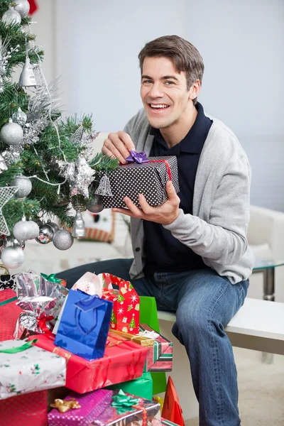 Щаслива людина з подарунками сидячи на різдвяній ялинці — стокове фото