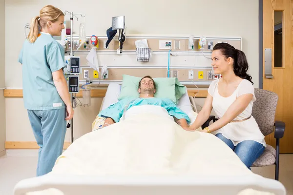 Vrouw van patiënt hand houden terwijl kijken naar verpleegster — Stockfoto