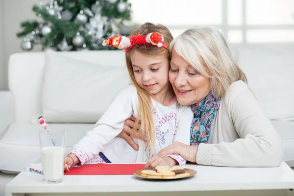 Mormor hjälpa flickan att skriva brev till jultomten — Stockfoto