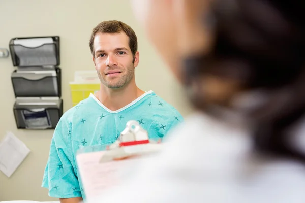 Patient med läkare i förgrunden på sjukhus — Stockfoto